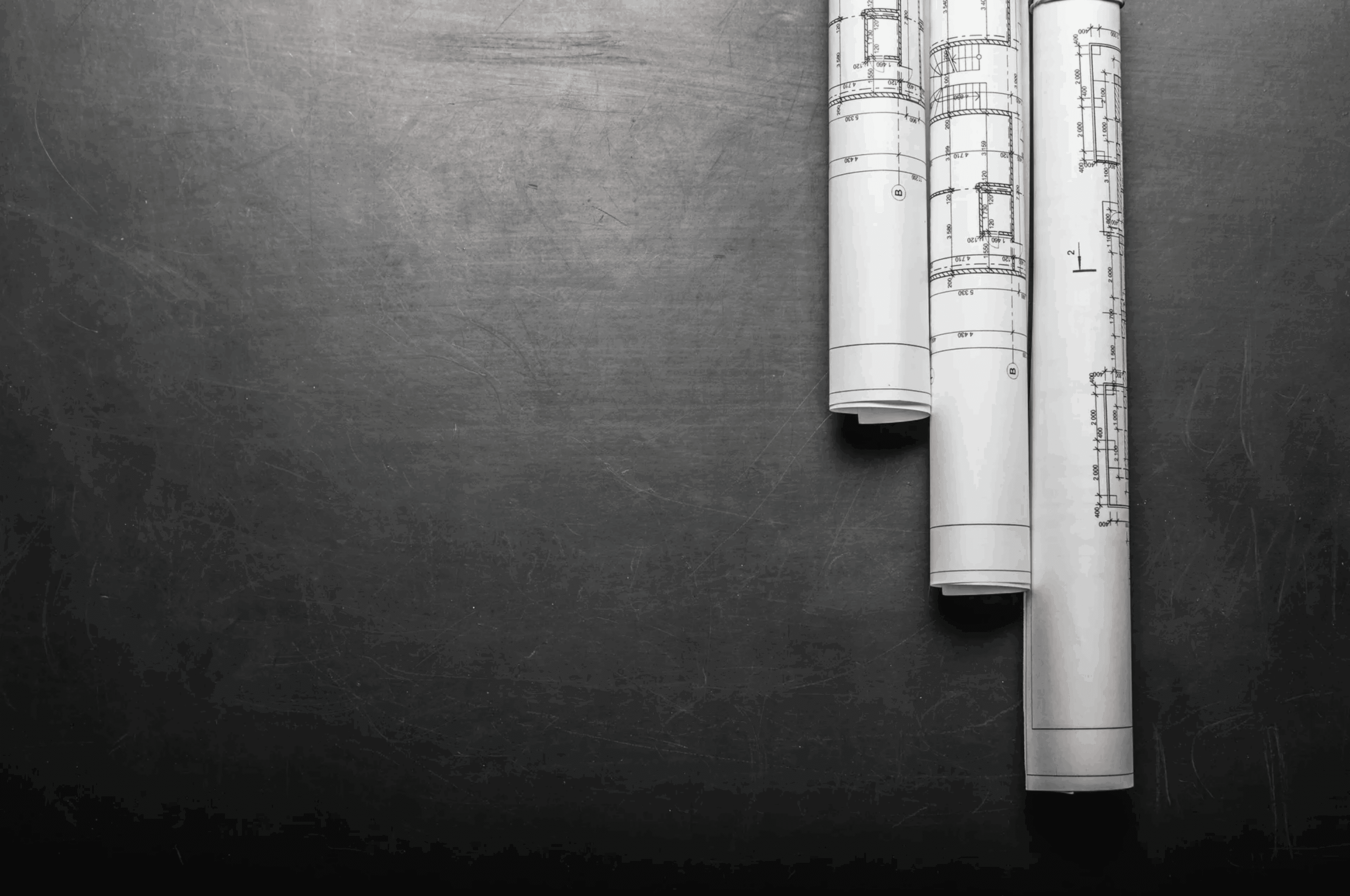 Rolled architectural plans on black surface